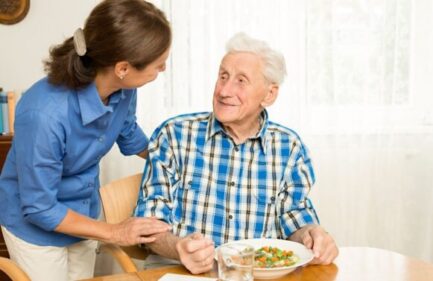 daughter giving elderly father dinner