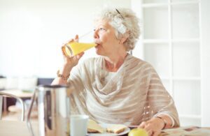 elderly woman drinking glass of pure orange juice