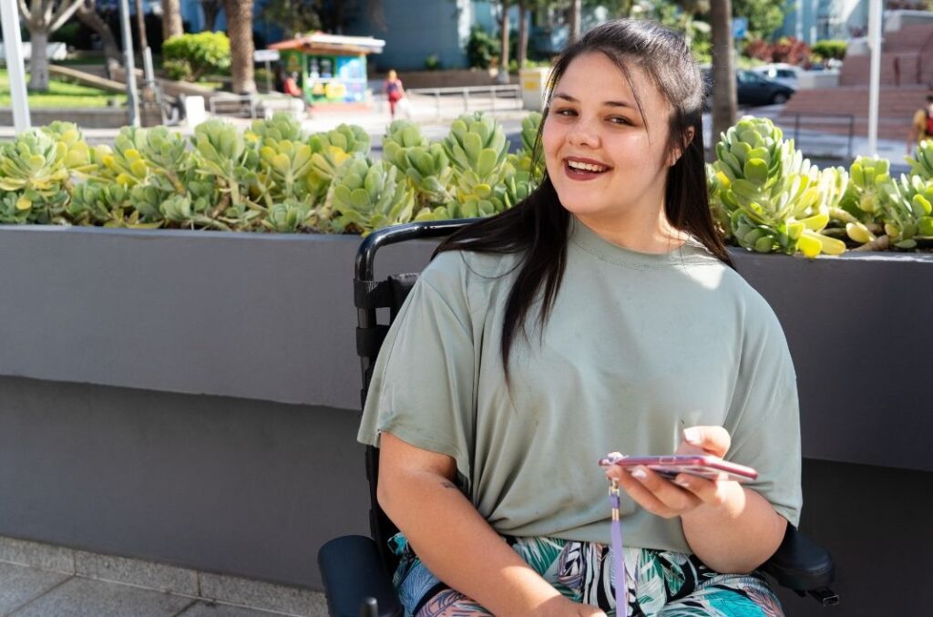 young woman sitting in a wheelchair holding her phone