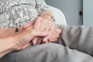 A young hand holds an elderly person’s hand