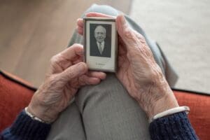 An elderly person holding black and white photograph in their lap