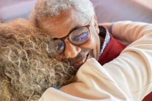 man with grey hair hugging and woman and smiling