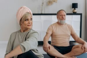 An older couple doing yoga in front room