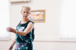older woman in black vest exercising in dance studio