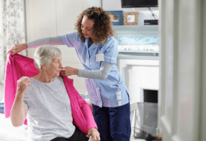 A nurse assists an elderly woman in bed, providing care and support in a healthcare setting