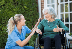 A woman in a wheelchair engages in conversation with another woman wearing a blue shirt