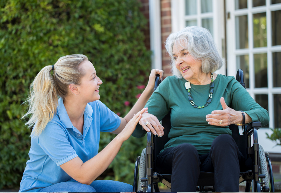 A woman in a wheelchair engages in conversation with another woman wearing a blue shirt