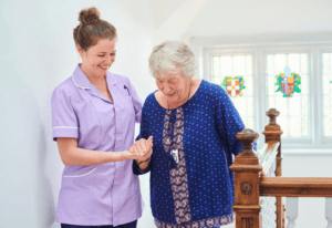 A nurse assists an elderly woman as she climbs a staircase, providing support and guidance for safe movement