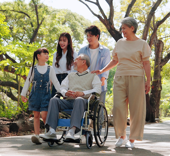 A family walks along a path, with a man in a wheelchair being pushed by a woman, enjoying their time together
