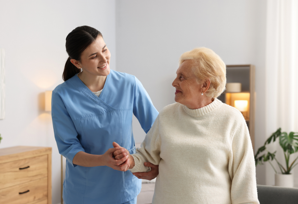A nurse assists an elderly woman in a home setting, providing care and support with a compassionate demeanor