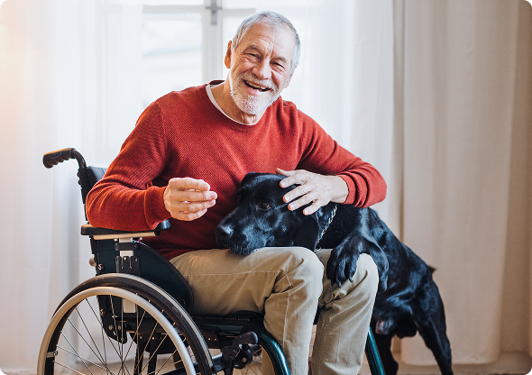 An older man in a wheelchair smiles while his dog sits beside him, showcasing their companionship